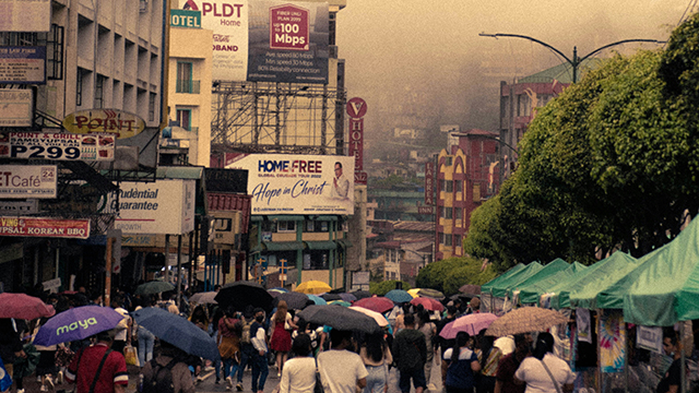 street in the philippines filled with smog and people walking through itr